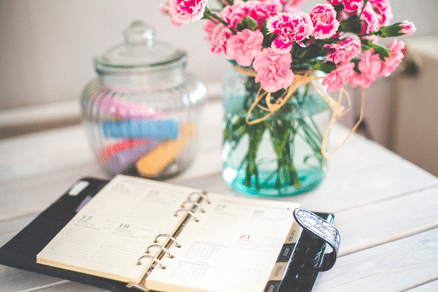 Celebration planning notebook on rustic wooden table with flowers - EventLavs.com