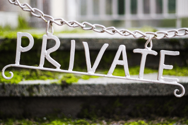 Metal sign reading "PRIVATE" hanging from a chain in front of moss-covered concrete steps, symbolizing restricted access or personal space.