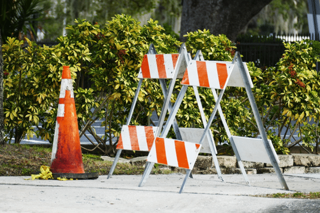 Orange traffic cone and striped barricades at a roadside construction site