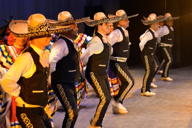 Traditional Mexican dancers in sombreros performing on stage.