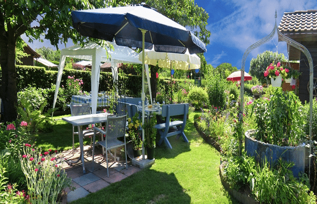 Backyard party setup with umbrellas and tables.