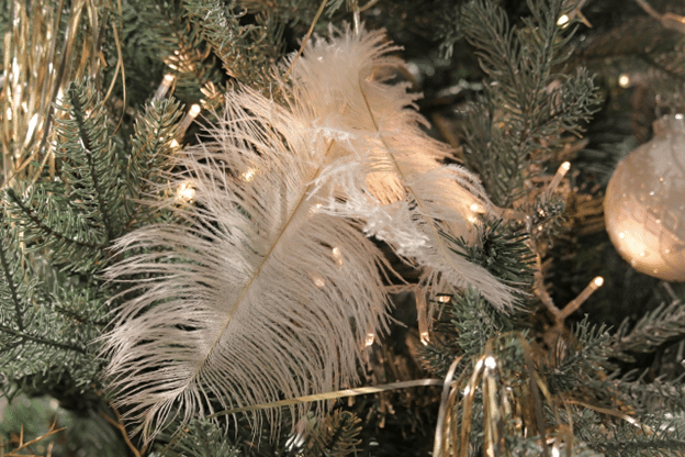 White feather accents and twinkle lights tucked into evergreen branches.