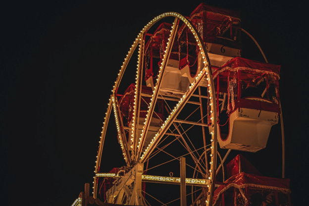 Ferris wheel glowing at night with red gondolas and marquee lights.